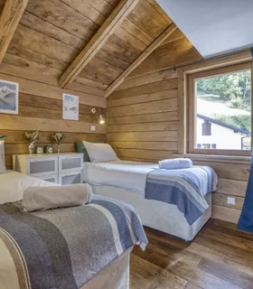 Chambre lumineuse avec 2 lits simples, idéale pour enfants ou amis Chambre twin lumineuse dans l’appartement Prakka High Camp à Les Houches – deux lits simples confortables, rangements et décoration alpine pour une location à Chamonix Mont Blanc.