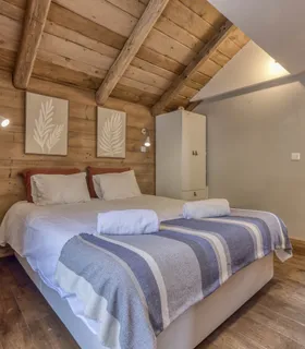 Chambre spacieuse avec lit double, ambiance bois et confort alpin Appartement Prakka High Camp à Les Houches – chambre double élégante avec literie haut de gamme, décoration chaleureuse et cadre calme à deux pas de Chamonix.