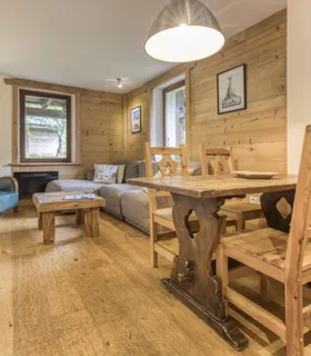 Grande table en bois et ambiance alpine pour vos repas Appartement Prakka Base Camp à louer à Chamonix – salle à manger en bois chaleureuse pour des vacances à la montagne.