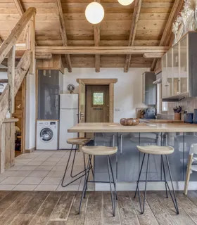 Cuisine américaine avec mange-debout et accès direct au séjour Cuisine ouverte du Prakka High Camp à Les Houches – appartement à louer avec équipements modernes à deux pas du domaine skiable des Houches.