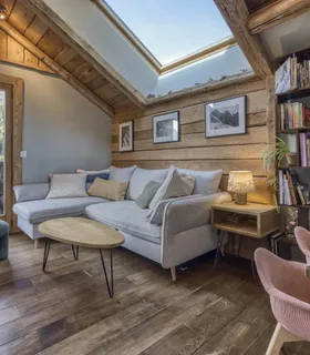 Salon chaleureux avec canapé et espace de travail face aux montagnes Salon du Prakka High Camp à louer à Les Houches – espace détente avec canapé, bureau et ambiance alpine face aux montagnes de Chamonix.