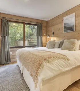 Chambre ensoleillée avec grandes fenêtres et vue montagne Appartement Prakka Base Camp à Les Houches – chambre parentale lumineuse avec décoration bois et vue sur les montagnes de Chamonix.