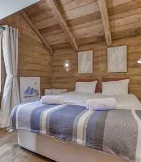 Grande chambre avec lit double et accès extérieur sur balcon privé Chambre principale avec lit double à louer dans le Prakka High Camp à Les Houches – décoration bois, accès direct au balcon, ambiance cosy proche de Chamonix Mont Blanc.