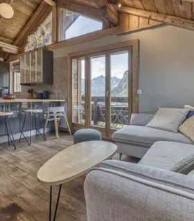 Salon lumineux et ambiance alpine dans un hébergement tout confort Appartement de vacances à Chamonix – salon confortable avec canapé et coin bureau dans le Prakka High Camp à Les Houches, ambiance chalet moderne.